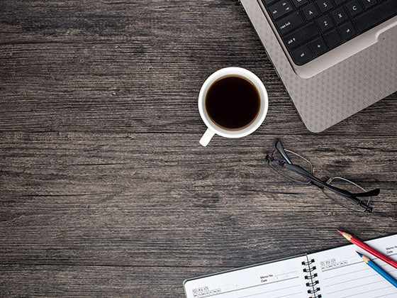 Office desk with laptop computer, planner, mobile smartphone and coffee cup.